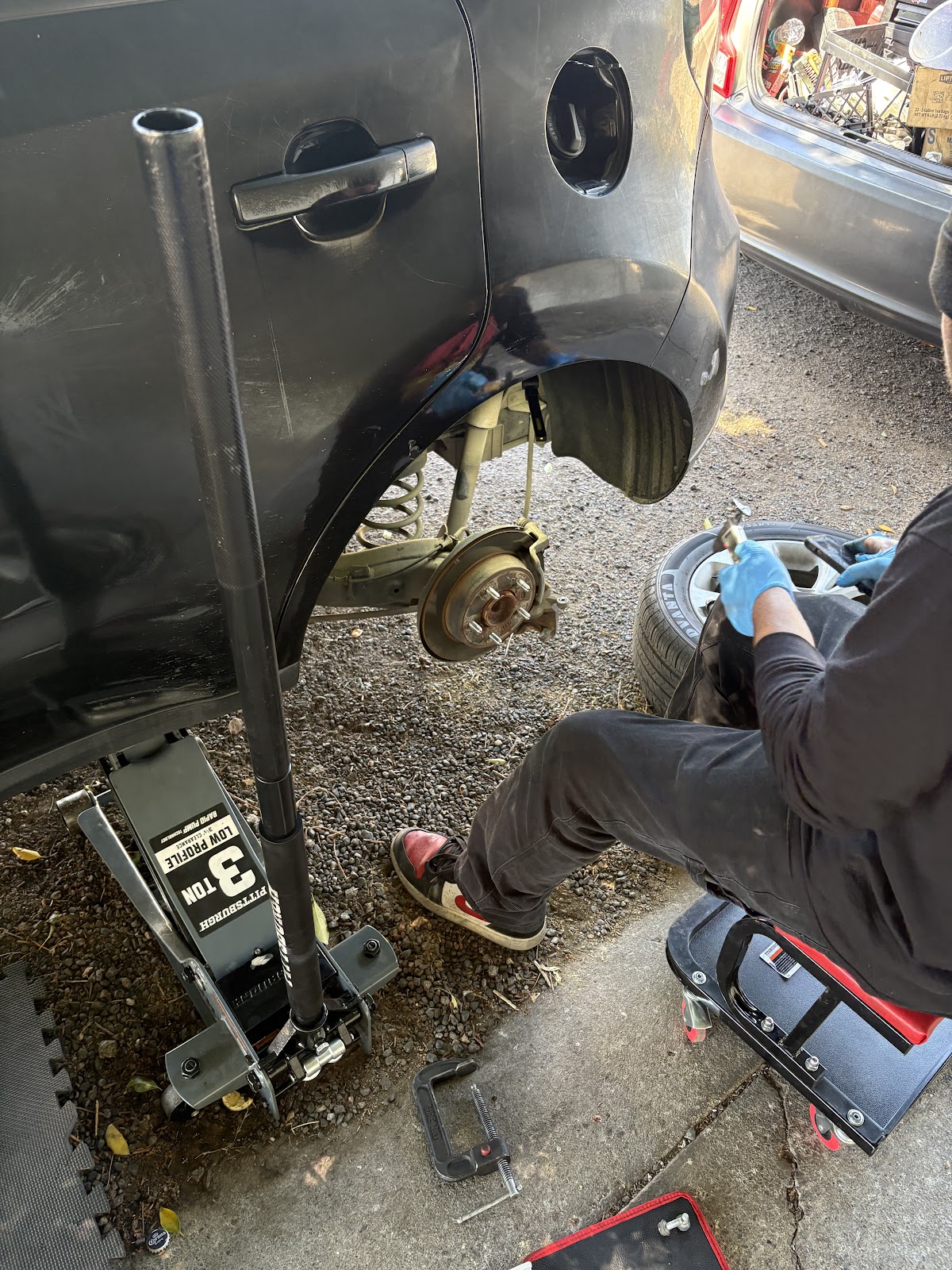Customer photo of the mechanic on a stool working the rear brakes with the wheel off