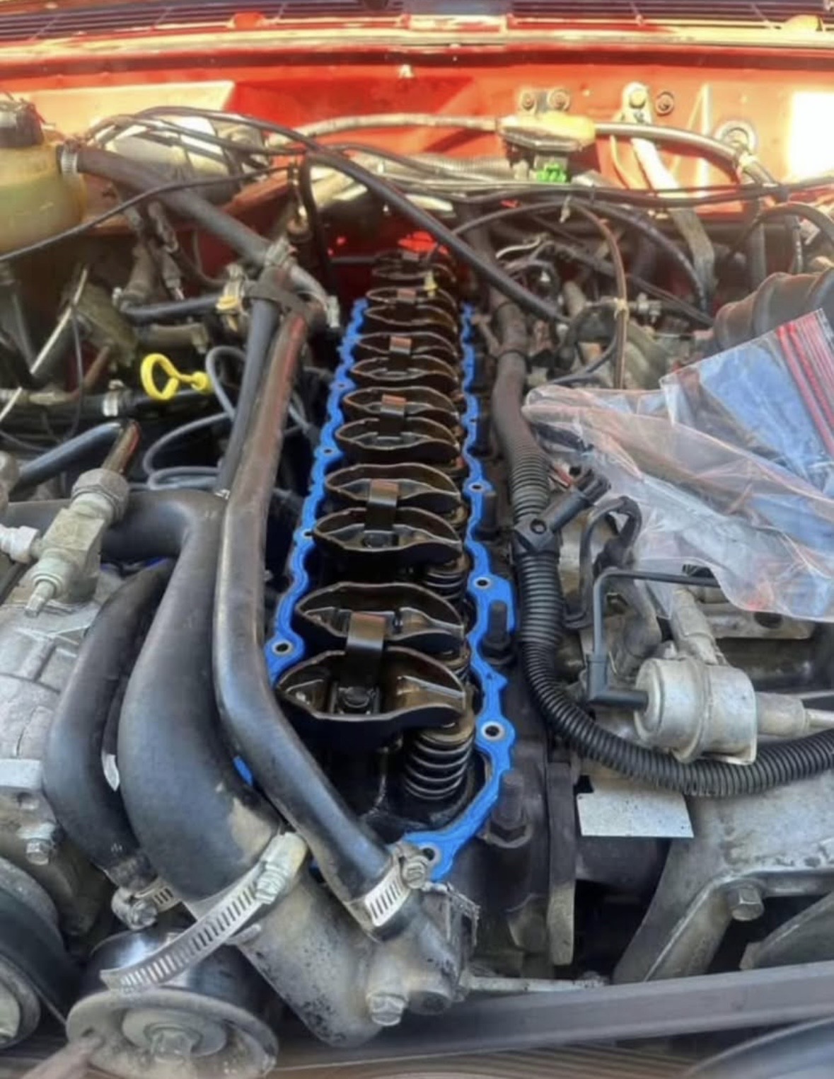 Inline six engine with the valve cover off, rocker arms exposed and a new blue gasket seated